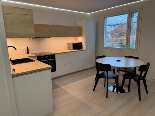 Una cocina con una mesa y sillas en una habitación. en Modern and spacious apartment with a separate bedroom, en Riihimäki