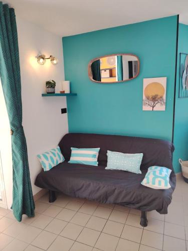 - un canapé dans une chambre dotée d'un mur bleu dans l'établissement Bel appartement au pied des pistes de serre chevalier, à Briançon