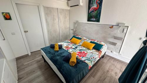 a small bedroom with a bed with yellow pillows at le Kalinao, Anse des Rochers plage, piscine et cocotiers in Saint-François