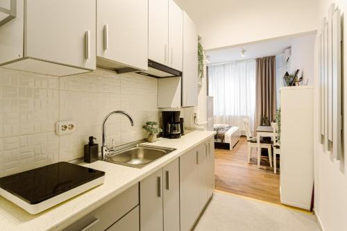 a white kitchen with a sink and a refrigerator at Heart of Bucharest - Cozy Studios on Smardan Street in Bucharest