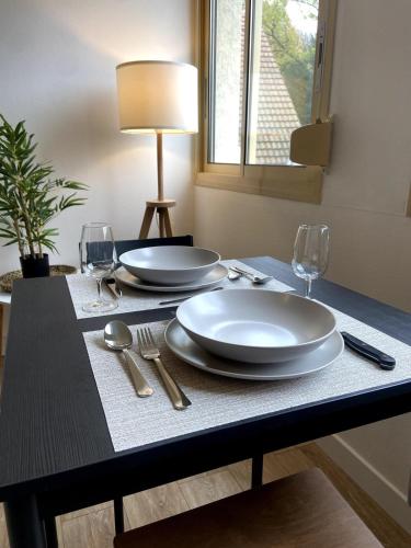 une table avec deux plaques blanches et de l'argenterie dans l'établissement Le Saint-Maimboeuf-Au calme dans une résidence privée-Parking gratuit, à Montbéliard