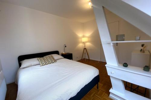 a bedroom with a white bed and a staircase at Le Saint-Maimboeuf-Au calme dans une résidence privée-Parking gratuit in Montbéliard