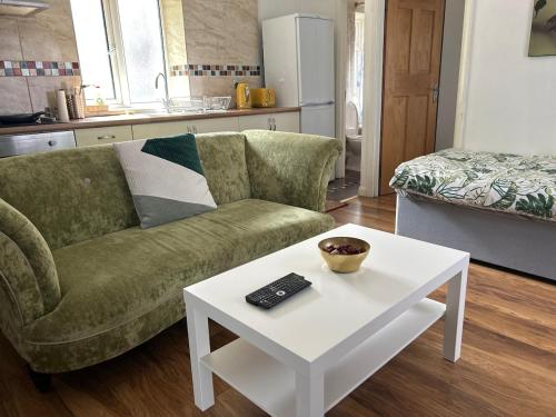 a living room with a green couch and a white table at Bright 1 bedroom apartment in central london in London