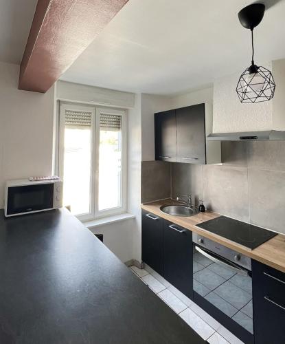 - une cuisine avec un plan de travail noir et un évier dans l'établissement Le Paisible d'Audincourt, à Audincourt