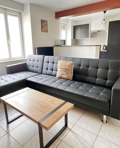 - un canapé noir dans le salon avec une table basse dans l'établissement Le Paisible d'Audincourt, à Audincourt