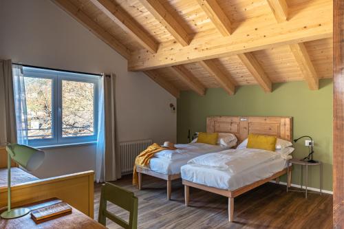MassimenoにあるCasa Cozzini - 3 appartamenti nella naturaのベッドが2つあり、天井が木製の寝室