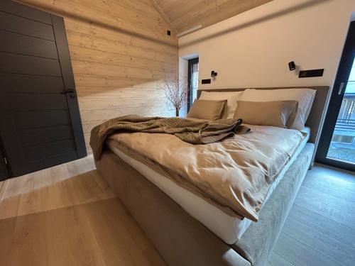 a large bed in a room with a wooden wall at Apartmány Dolina in Demanovska Dolina