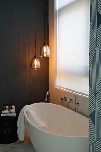 a bath tub in a bathroom with two pendant lights at Labotessa Luxury Boutique Hotel in Cape Town