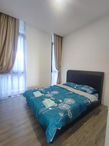 a bedroom with a bed with a blue comforter and a window at Kuching Podium Apartment Near Aeon Mall 3rd Mile in Kuching