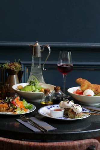 a table with plates of food and a glass of wine at Labotessa Luxury Boutique Hotel in Cape Town