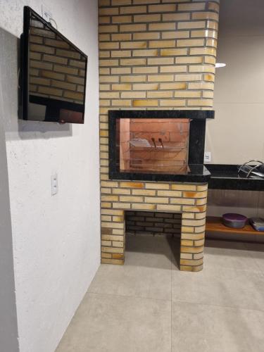 a brick fireplace with a tv on top of it at Residencial do Angelo - Pinheira in Pinheira