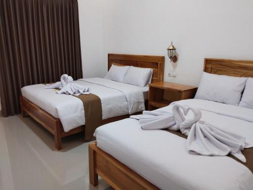 a hotel room with two beds with white sheets at Nan Bungalows Tetebatu in Tetebatu