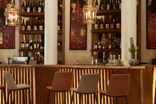a bar with brown chairs and bottles of alcohol at Nobu Hotel Marrakech in Marrakech