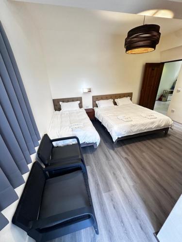 two beds and a chair in a room at Guoxiang B&B in Taitung City