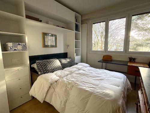 une chambre avec un lit, un bureau et des fenêtres dans l'établissement L'appartement Dantan, à Saint-Cloud