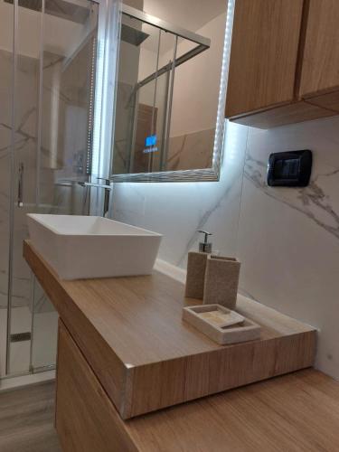 a bathroom with a white sink on a wooden counter at 4 Piano Apartment in Laveno-Mombello