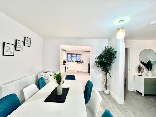 a dining room with a white table and blue chairs at Stunning Five Bedroom Holiday Home in Chartham Canterbury with Hot Tub in Chartham