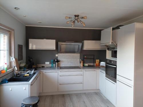 a kitchen with white cabinets and a ceiling fan at Une chambre privée au sein d'une villa à la campagne in Wanze