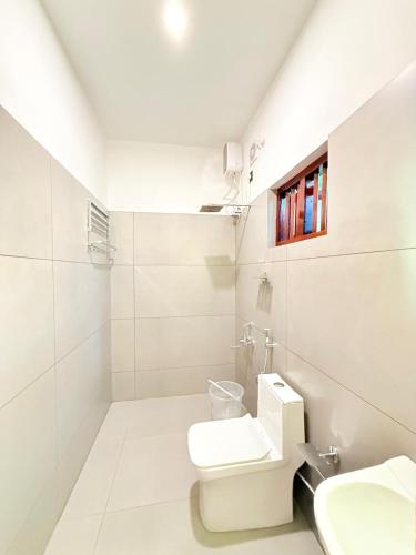 a white bathroom with a toilet and a sink at Credible Heritage Resort in Varkala