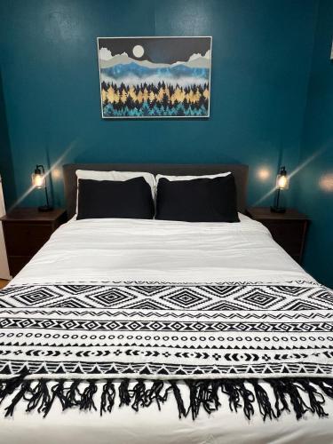 a bed with a black and white blanket on it at Eco-Friendly Sunnyside 3 Bedroom Bungalow in Denver