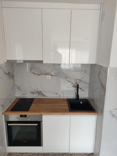 a kitchen with white cabinets and a sink at Apartman Sale lux in Leskovac