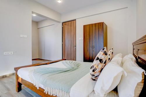 a bedroom with a bed with white sheets and pillows at ELIVAAS 3 BHK Aamy Villa with Pvt Pool & Garden in Lonavala