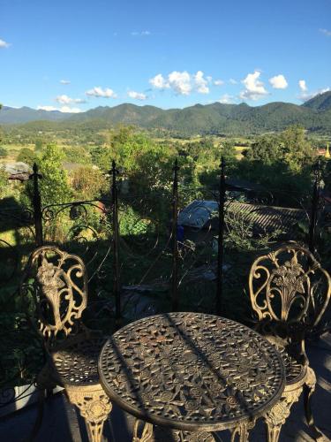 a table and chairs on a balcony with a view at Villa Wolfsbau in Pai