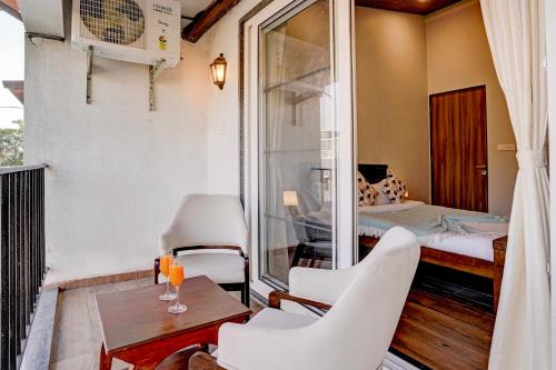 a room with a balcony with a bed and a table and chairs at ELIVAAS 3 BHK Aamy Villa with Pvt Pool & Garden in Lonavala