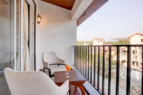 a balcony with white chairs and a table and a window at ELIVAAS 3 BHK Aamy Villa with Pvt Pool & Garden in Lonavala