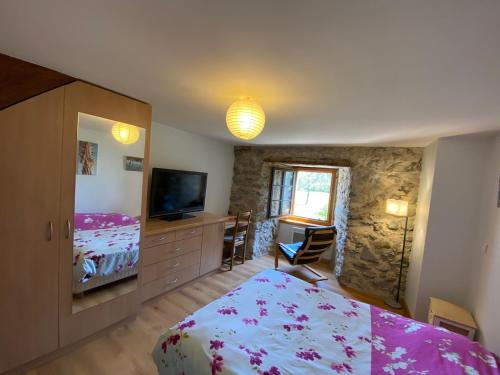 une chambre avec un lit et une commode avec une télévision dans l'établissement Maison de village, à Yvoire