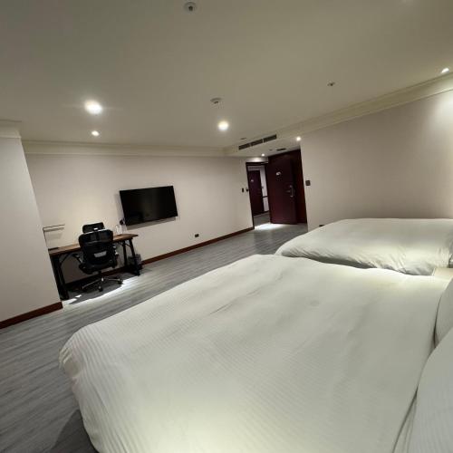 a bedroom with two beds and a flat screen tv at XinsheHotel - Chungli in Zhongli