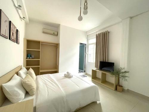 a white bedroom with a bed and a television at Ann Home in Ho Chi Minh City
