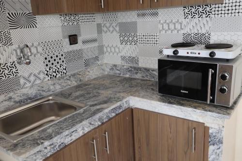 a kitchen with a sink and a microwave at Appart-Hôtel BEL ANFA in Casablanca