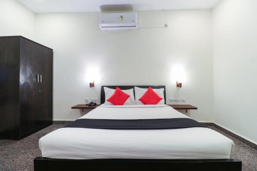 a bedroom with a large bed with red pillows at Capital O GN Suites in Bengaluru