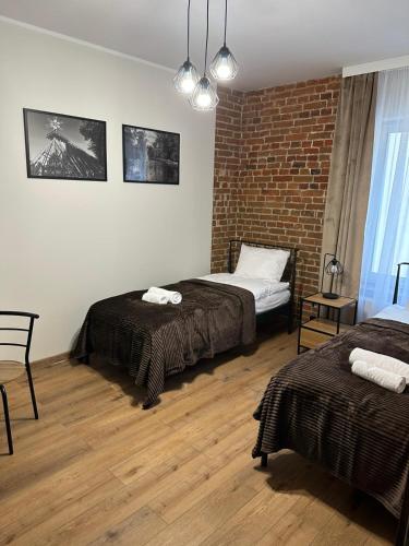 a bedroom with two beds and a brick wall at Kamienica LOFT in Ciechocinek