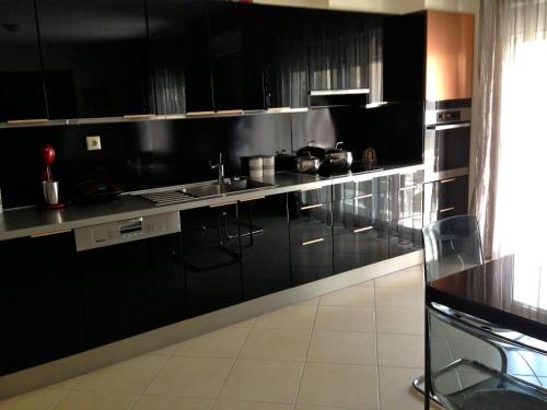 een keuken met zwarte kasten en een wastafel bij REM Apartments in Thessaloniki