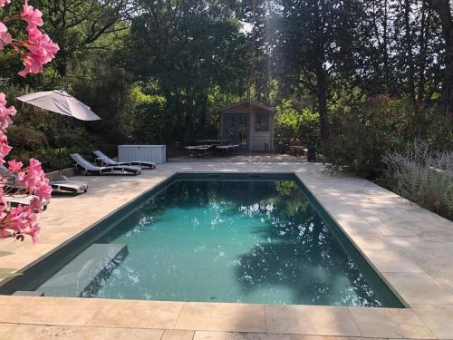 a swimming pool in a yard with a table and umbrella at La Villa du Castel in Auriol