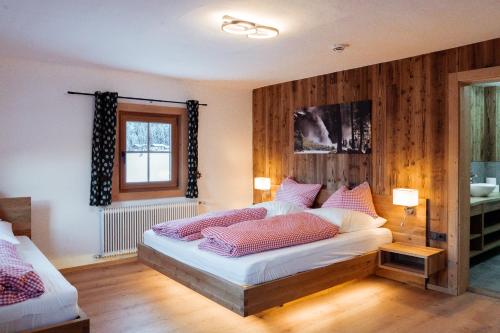 a bedroom with a large bed with a wooden wall at SÖLLHOF Ferienhaus mit 11 Schlafzimmern I großer Gemeinschaftsraum I Skibushaltestelle I 10 Min zum Skigebiet in Krimml