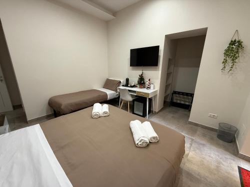 a room with two beds and a desk and a television at Stay In Naples - Arenaccia 211 Rooms and Suite in Naples