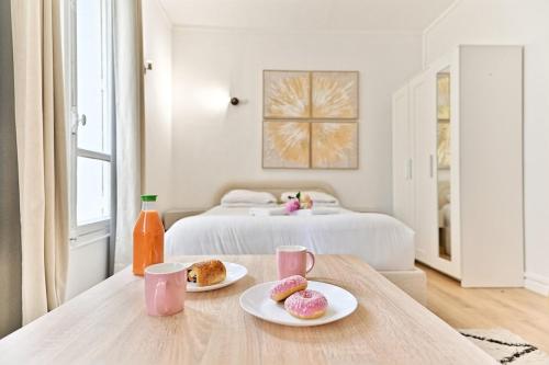 une chambre avec un lit et deux plaques de beignets sur une table dans l'établissement Peaceful Studio Parc des Buttes-Chaumont - II, à Paris