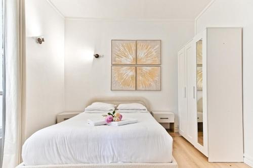 - une chambre blanche avec un lit blanc orné de fleurs dans l'établissement Peaceful Studio Parc des Buttes-Chaumont - II, à Paris
