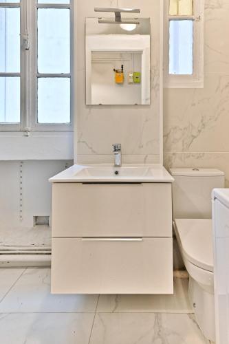une salle de bain blanche avec un lavabo et un miroir dans l'établissement Peaceful Studio Parc des Buttes-Chaumont - II, à Paris