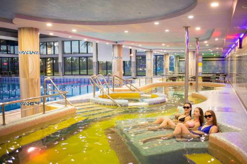 two women sitting in an indoor swimming pool at Європа готель in Solomonovo