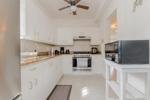 a kitchen with white cabinets and a ceiling fan at CHIC Lagoon front Villa by Casa Paraíso in Cancún