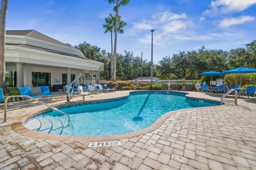 a swimming pool with chairs and umbrellas next to a house at HSO - Family Apartments Close to Disney World & Universal in Orlando