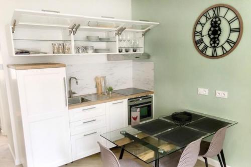 une cuisine avec une table et une horloge au mur dans l'établissement Le Fremyot : Apt 4 prs, 2 ch, proche Darcy et Gare, à Dijon