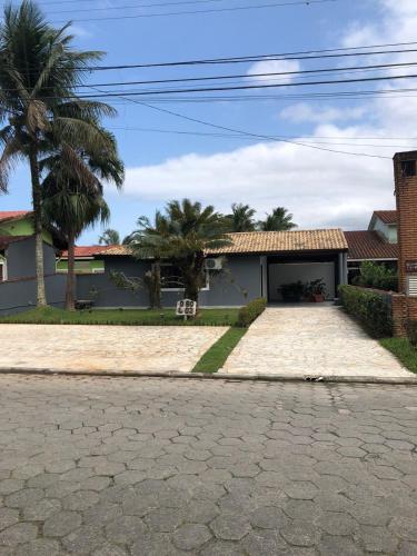 a house with a palm tree and a driveway at Casa Maldonado Morada da Praia 4 suítes in Bertioga