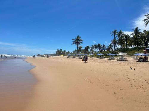 einen Strand mit Stühlen und Sonnenschirmen und Menschen darauf in der Unterkunft Praia do Flamengo 150m da praia Casa Ballalai in Salvador