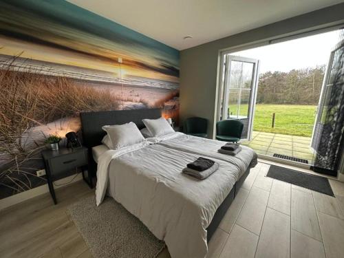 a bedroom with a large bed and a large window at Buiten Gewoon in De Koog