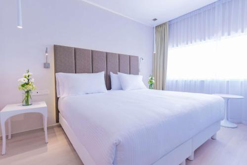 a white bedroom with a large white bed and a window at NH Puebla FINSA in Puebla